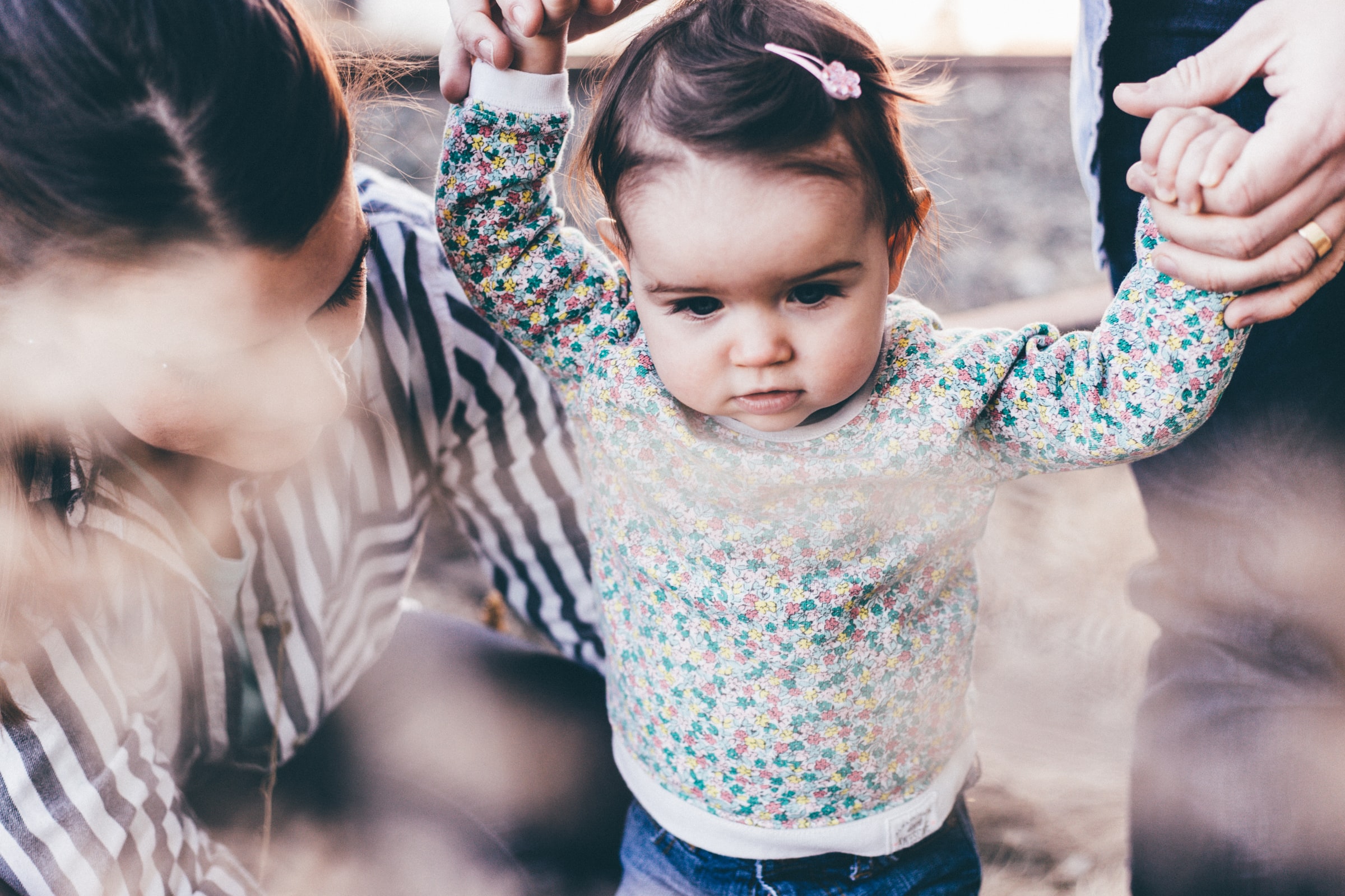 A young child taking supported steps, symbolizing the beginning of lifelong learning and growth, courtesy of OCDC's programs.